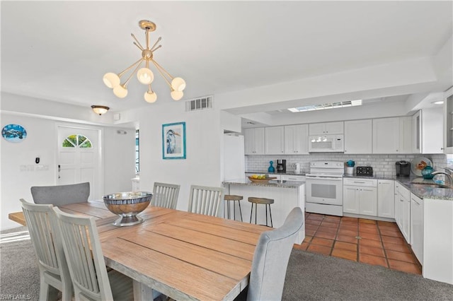 dining area featuring dark colored carpet, a notable chandelier, and sink