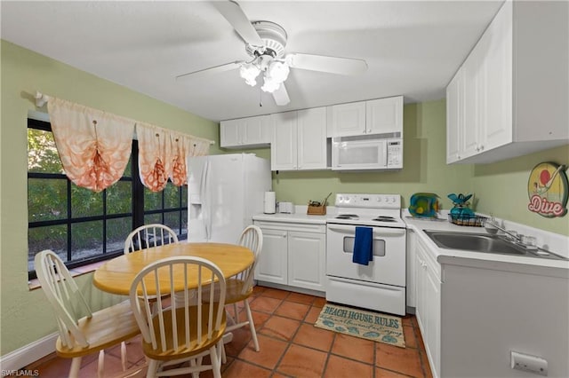 kitchen with white appliances, white cabinetry, dark tile flooring, and ceiling fan