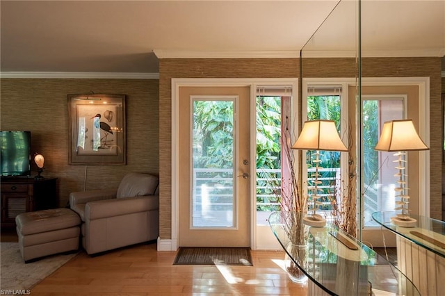 doorway to outside with light hardwood / wood-style floors, ornamental molding, and a wealth of natural light