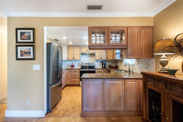 kitchen with kitchen peninsula, appliances with stainless steel finishes, sink, light hardwood / wood-style flooring, and tasteful backsplash