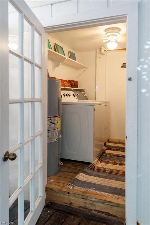 laundry area featuring washing machine and clothes dryer, water heater, and dark wood-type flooring