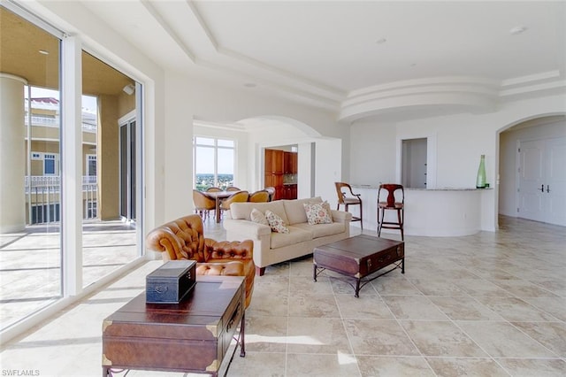 living room with a raised ceiling, light tile flooring, and ornamental molding