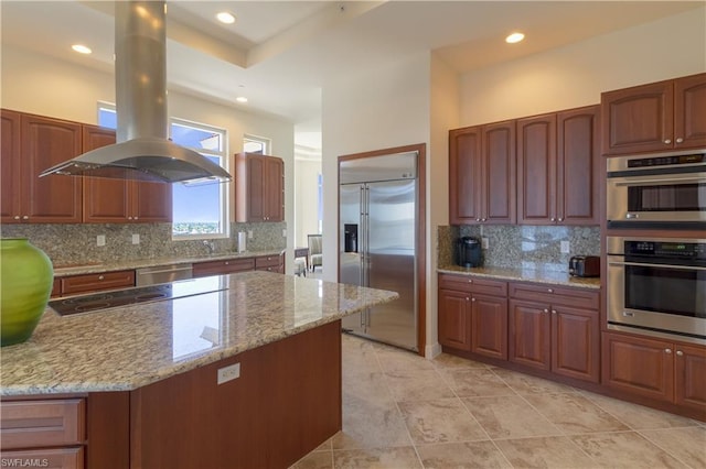 kitchen with light stone counters, appliances with stainless steel finishes, light tile flooring, island range hood, and tasteful backsplash