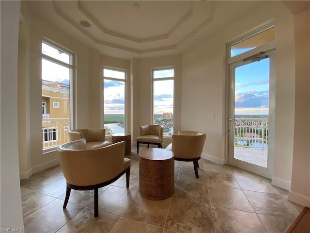 sitting room with a raised ceiling and light tile floors