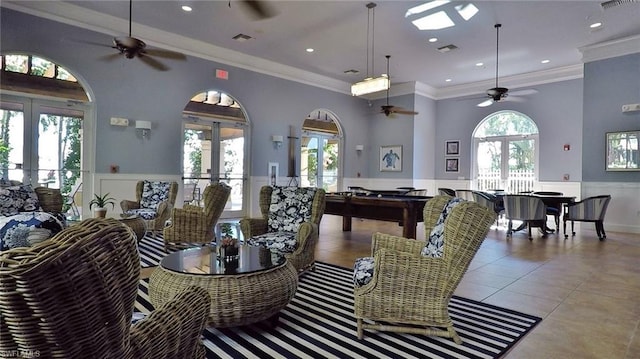 interior space with french doors, ceiling fan, light tile floors, ornamental molding, and a high ceiling