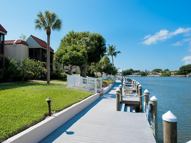 view of dock with a water view and a yard