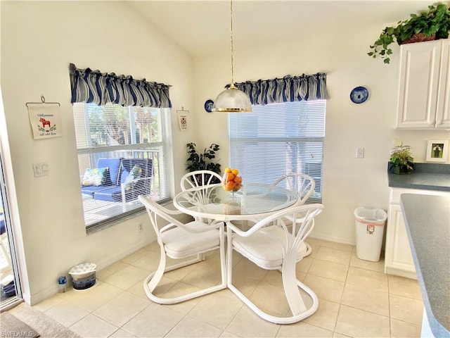 dining area with light tile floors and vaulted ceiling