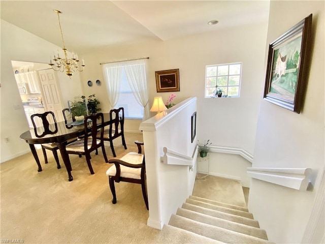 staircase with light carpet and a notable chandelier