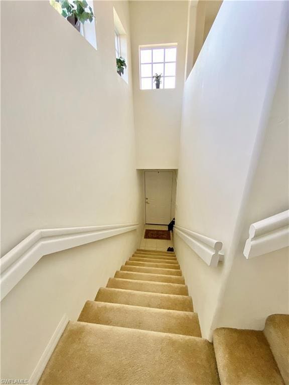 staircase with light carpet and a high ceiling