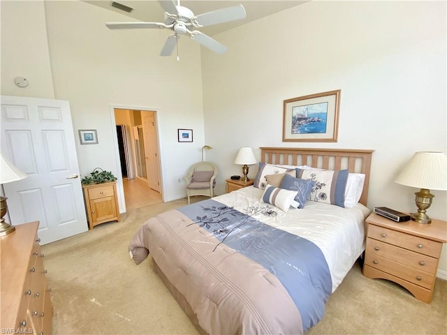 carpeted bedroom with connected bathroom, ceiling fan, and a towering ceiling