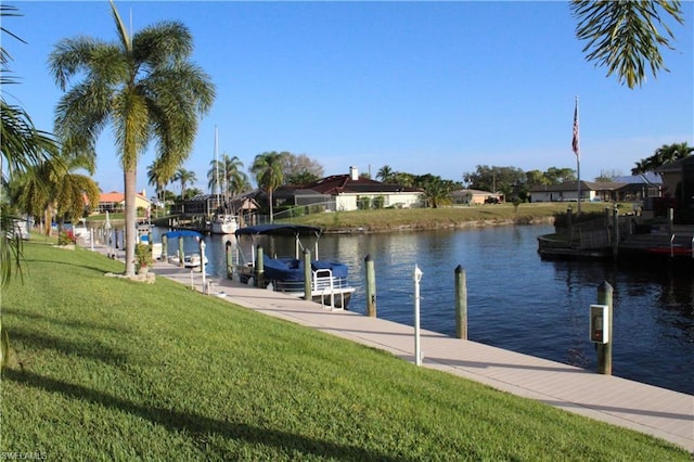 view of dock with a water view and a lawn