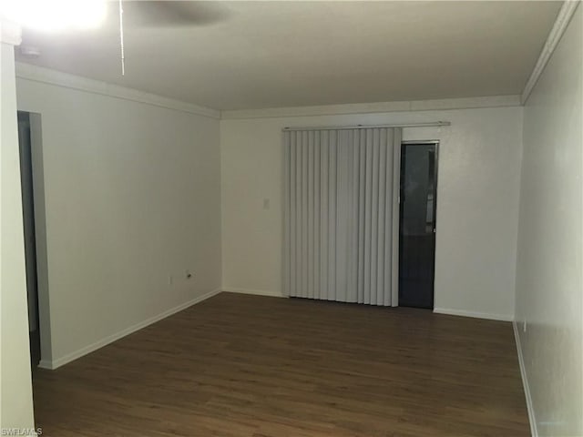 empty room featuring ornamental molding and dark wood-type flooring