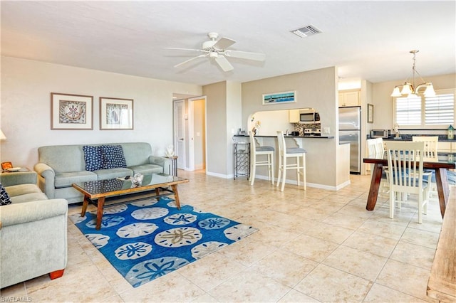 tiled living room with ceiling fan with notable chandelier