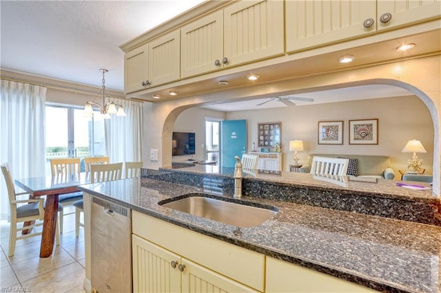 kitchen with sink, pendant lighting, dark stone counters, dishwasher, and ceiling fan with notable chandelier