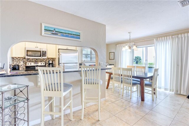 kitchen featuring a chandelier, tasteful backsplash, appliances with stainless steel finishes, and a wealth of natural light