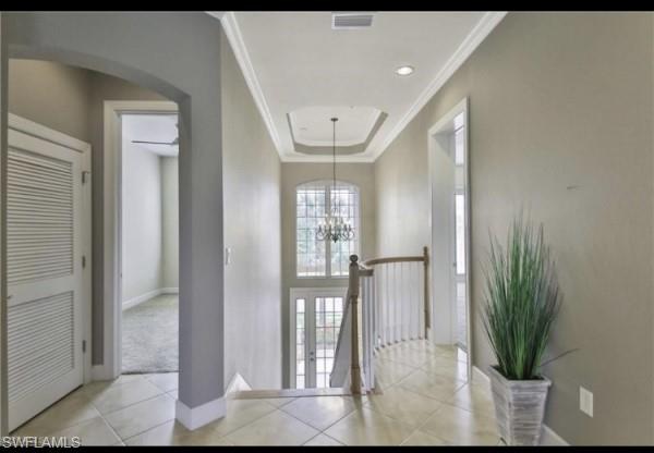 interior space with a chandelier, a tray ceiling, and ornamental molding