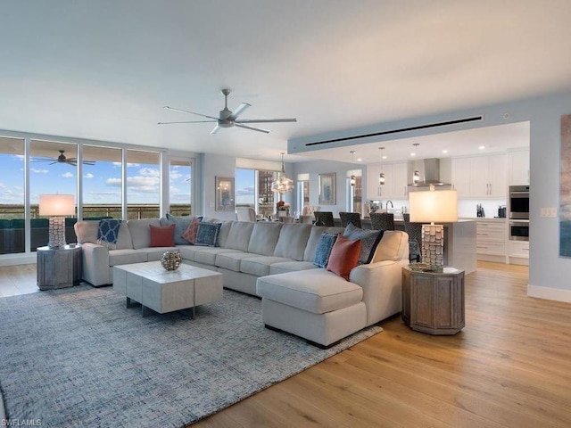 living room with light hardwood / wood-style floors, ceiling fan with notable chandelier, and sink