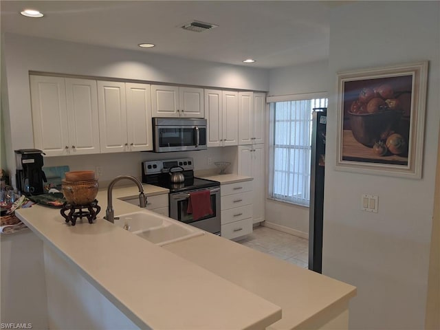 kitchen featuring kitchen peninsula, white cabinetry, appliances with stainless steel finishes, sink, and light tile floors