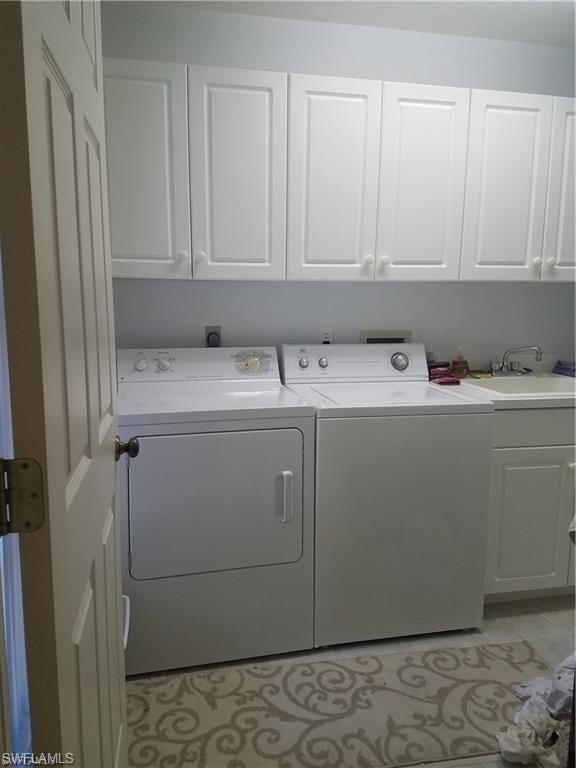 washroom with washing machine and clothes dryer, cabinets, and sink