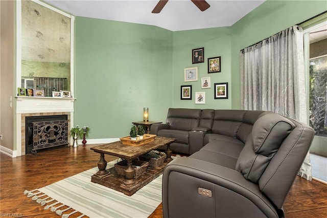 living room featuring ceiling fan, dark hardwood / wood-style floors, and a tile fireplace