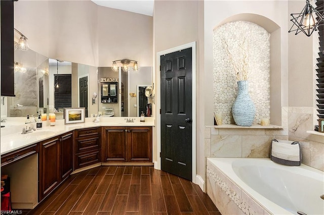 bathroom featuring double sink vanity, vaulted ceiling, hardwood / wood-style flooring, and tiled bath