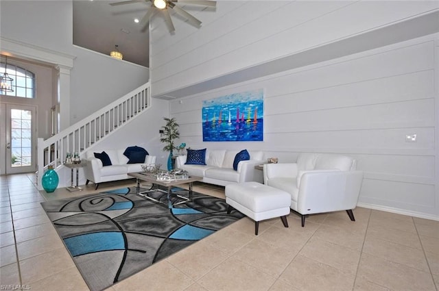 living room featuring ceiling fan, light tile floors, and a towering ceiling