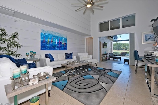 living room featuring light tile floors, ceiling fan, and a towering ceiling