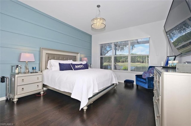 bedroom with dark hardwood / wood-style floors and an inviting chandelier