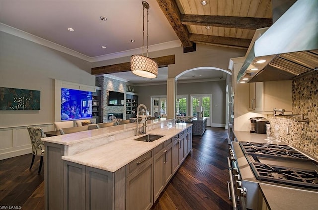 kitchen featuring sink, hanging light fixtures, fume extractor, a fireplace, and tasteful backsplash