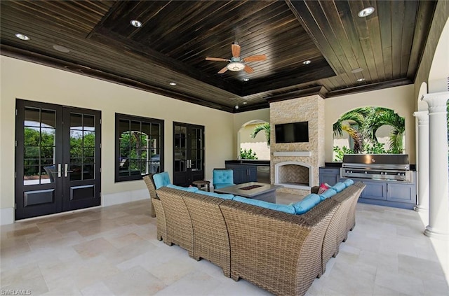 view of terrace featuring ceiling fan, a grill, area for grilling, a stone fireplace, and french doors