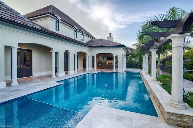 view of swimming pool with french doors, pool water feature, and a patio