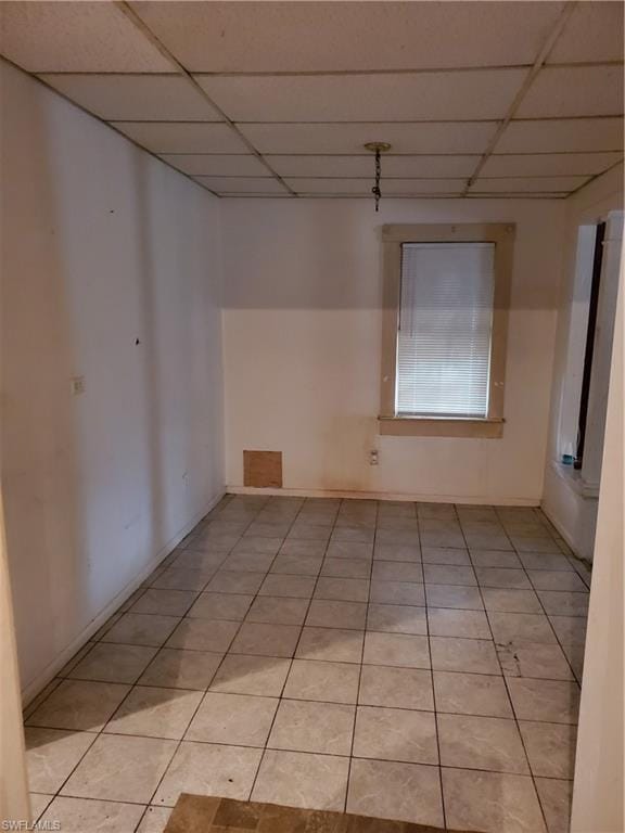 unfurnished room featuring a paneled ceiling and light tile floors