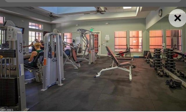 gym featuring ceiling fan and a tray ceiling