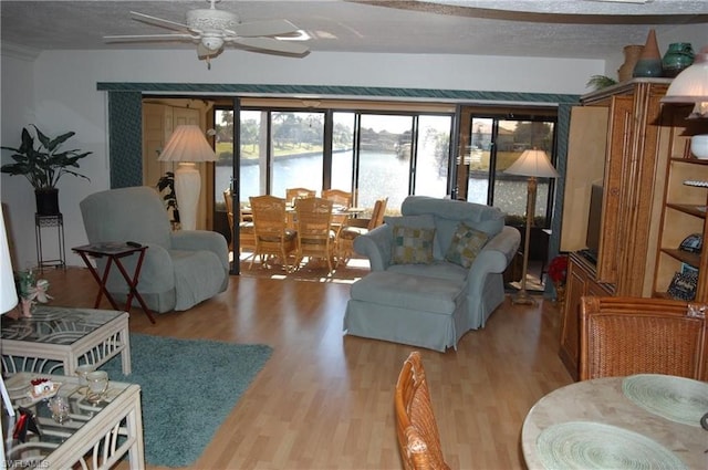 living room featuring a textured ceiling, light hardwood / wood-style flooring, ceiling fan, and a water view