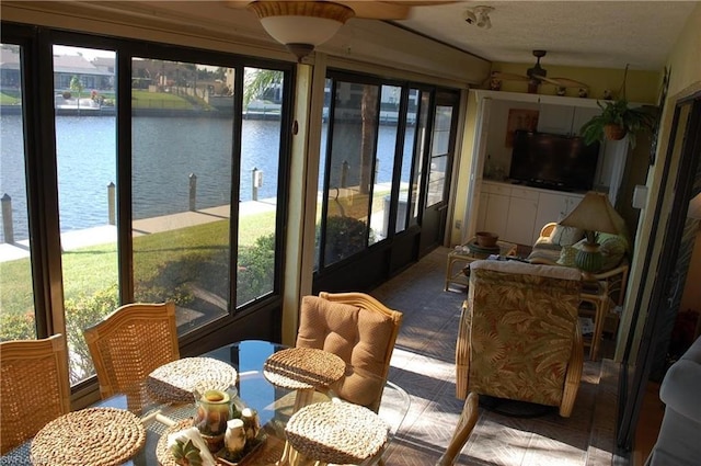 sunroom featuring a water view, ceiling fan, and a wealth of natural light