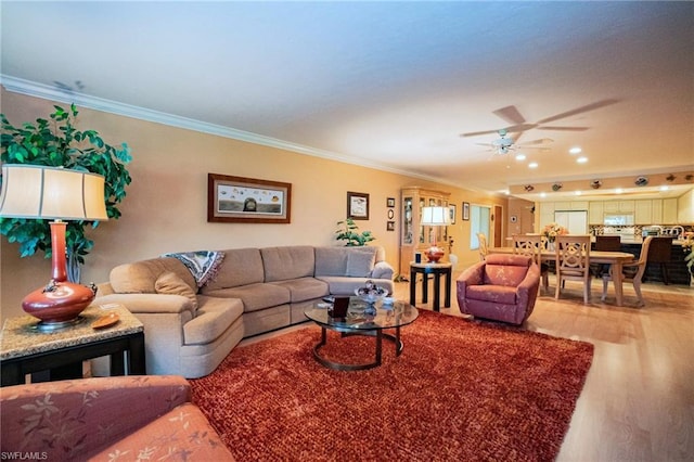 living room featuring ornamental molding, ceiling fan, and light wood-type flooring