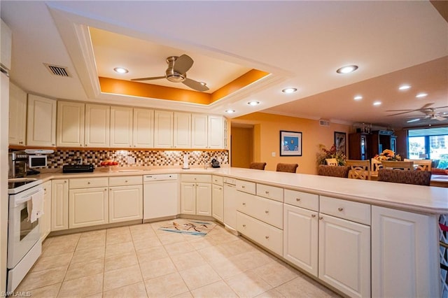 kitchen featuring white appliances, kitchen peninsula, ceiling fan, and a raised ceiling