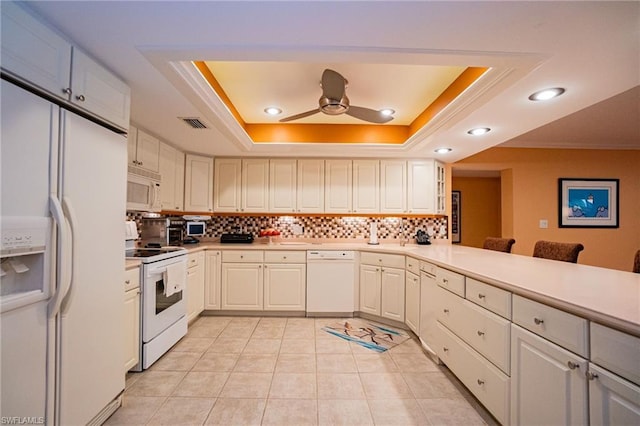 kitchen featuring a raised ceiling, tasteful backsplash, white appliances, and ceiling fan