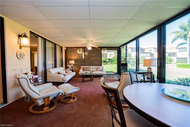 dining area with plenty of natural light, ceiling fan, a drop ceiling, and a wall of windows