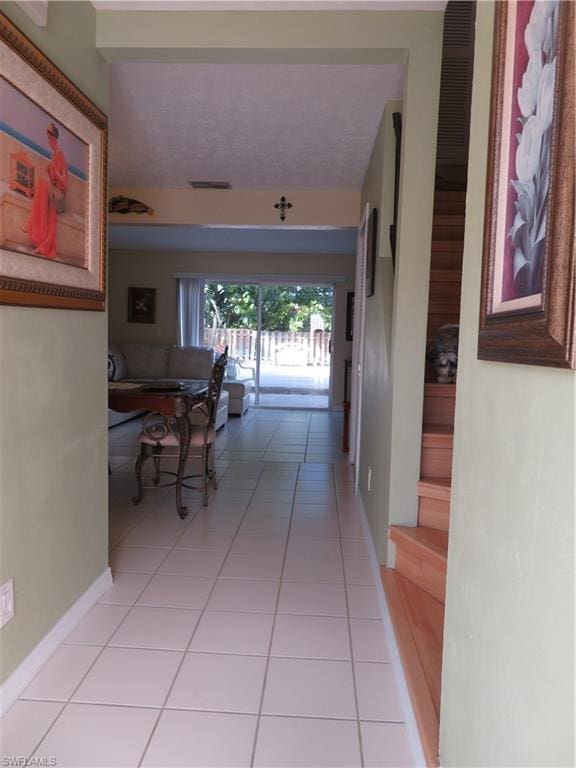 corridor with light tile floors and a textured ceiling