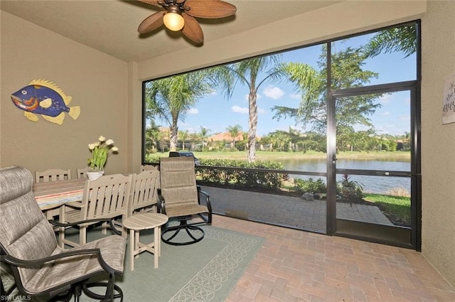 sunroom / solarium with a water view and ceiling fan