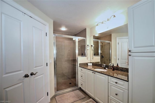 bathroom with tile floors, a shower with shower door, and large vanity