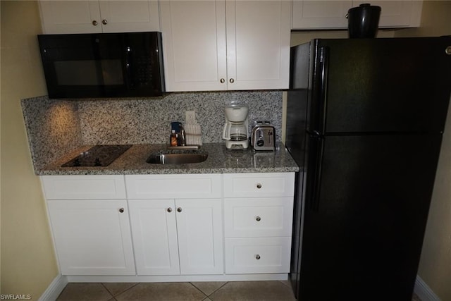 kitchen featuring light tile floors, dark stone counters, tasteful backsplash, black appliances, and white cabinetry