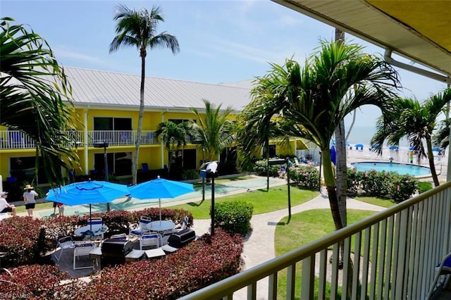 view of property's community featuring a swimming pool, a lawn, and a patio