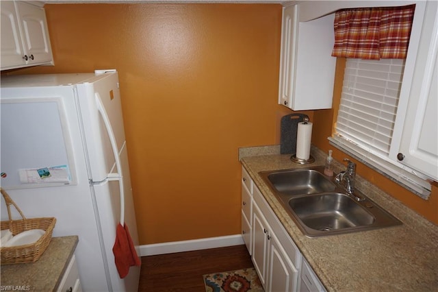 kitchen featuring white fridge, white cabinetry, dark wood-type flooring, and sink