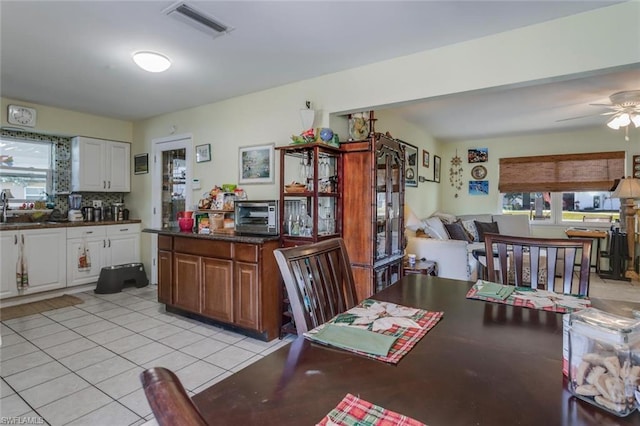 tiled dining room with ceiling fan, sink, and a wealth of natural light