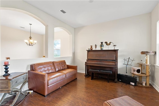 living room with dark wood-type flooring and an inviting chandelier