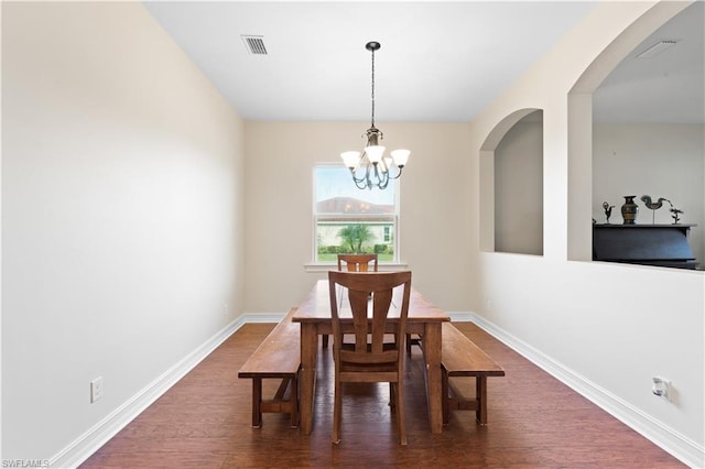 dining space with dark hardwood / wood-style flooring and an inviting chandelier