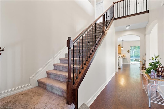 stairs with dark hardwood / wood-style floors and a towering ceiling