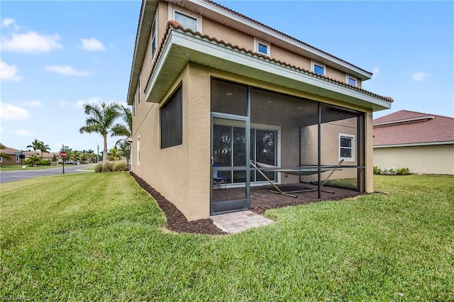 back of house with a lawn and a sunroom